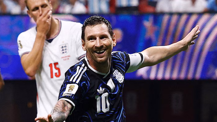 Lionel Messi smiles while an opponent looks on disapprovingly.