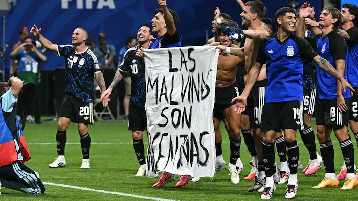 Argentine players hold a banner that reads 'the Malvinas are Argentine.'