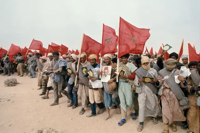 Moroccan civilians during the 1975 Green March holding national flags and portraits of King Hassan II